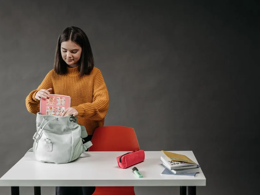 Une enfant range ses fournitures dans son cartable
